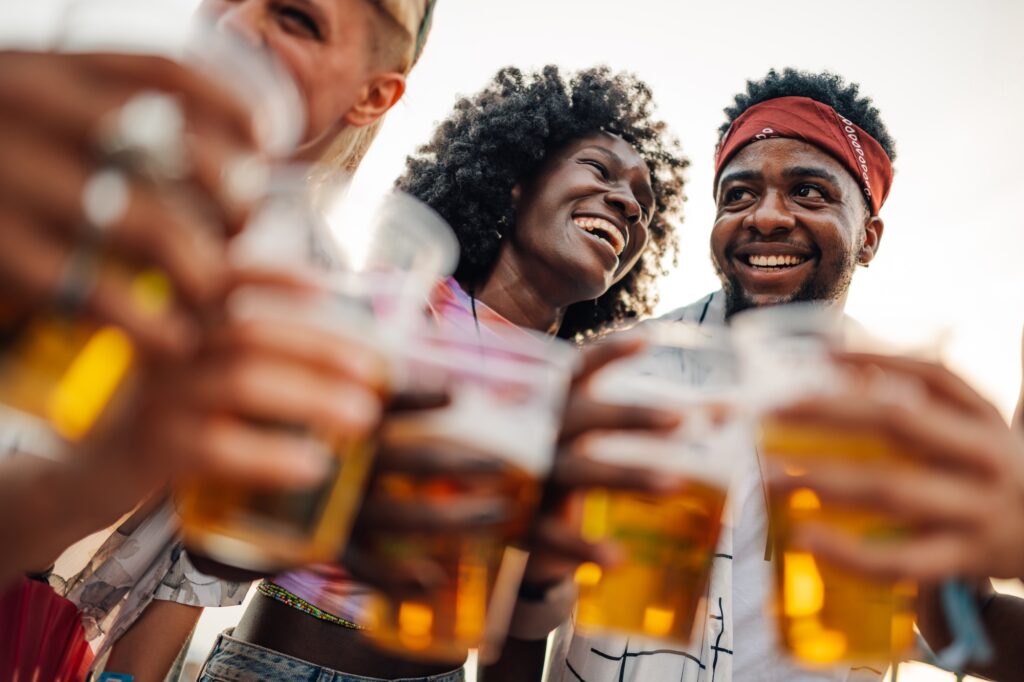 Happy friends toasting with beer at music festival